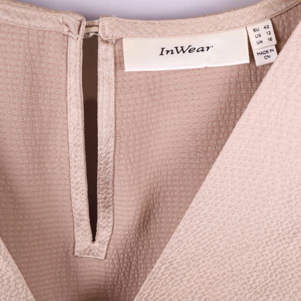 Närbild på v-ringning och märkning InWear i blus