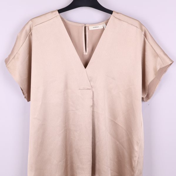 Helbild av beige blus med strukturerat tyg och korta ärmar