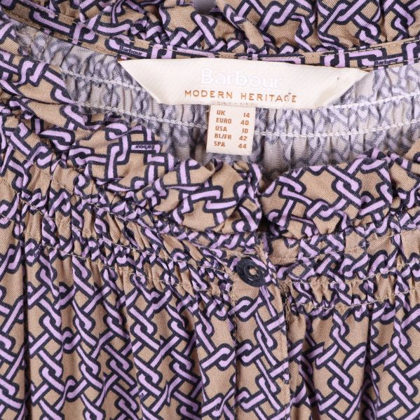 Detaljbild på halsringning och Barbour-etikett på klänning