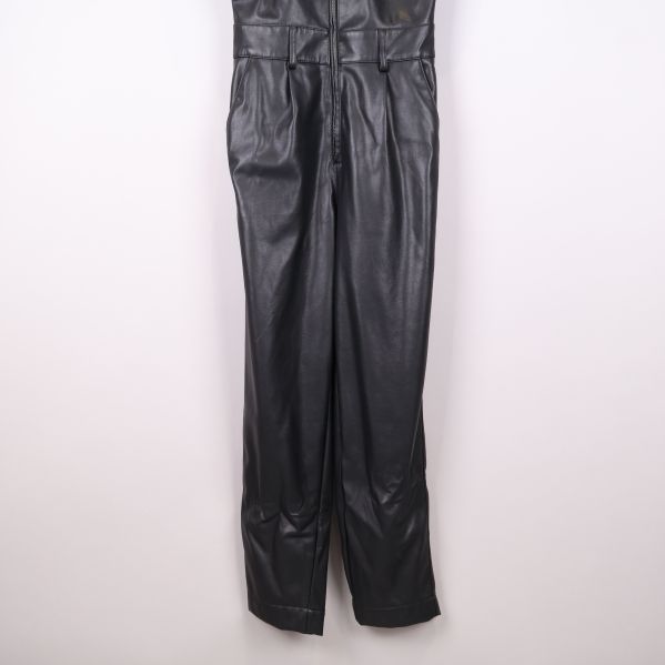 Byxbenen på jumpsuit i svart konstläder upphängda