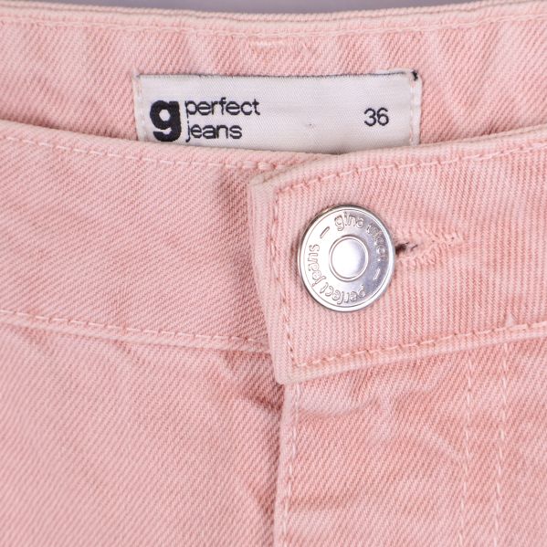 Närbild på midja och knapp med etikett 'perfect jeans' storlek 36
