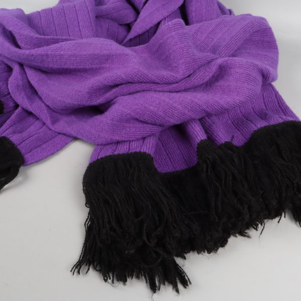 Uppackad lila halsduk med svarta fransar liggande