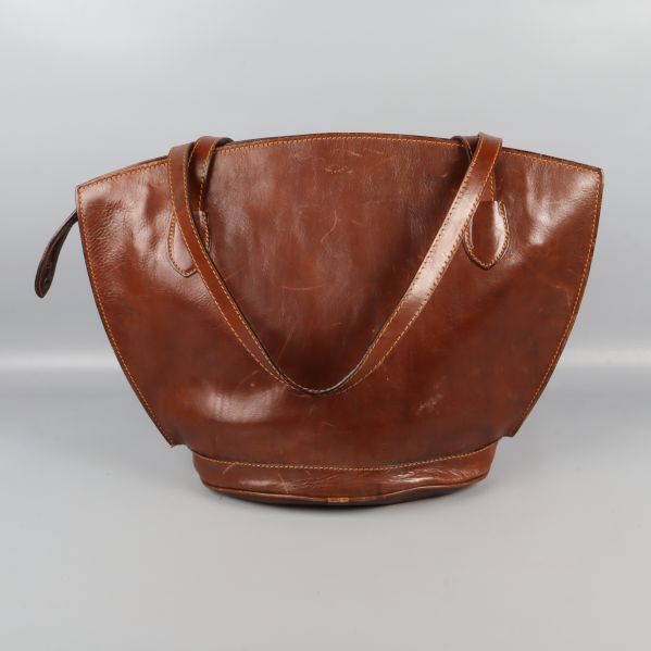 Baksidan av brun läderväska med axelremmar