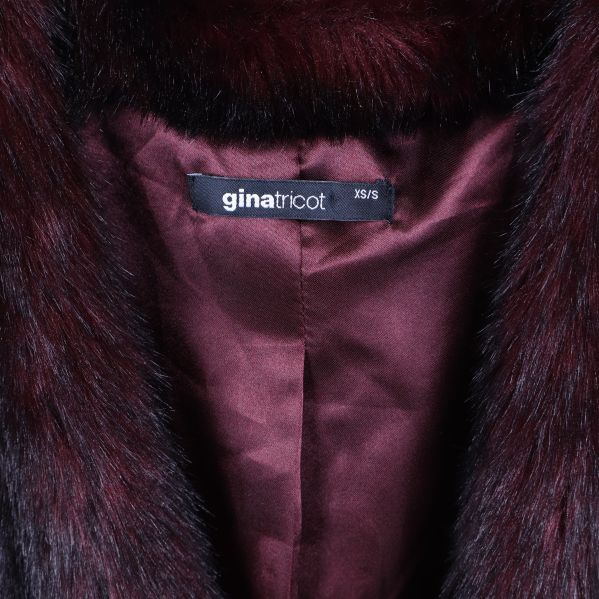 Närbild på Gina Tricot-märke och satinlining i väst