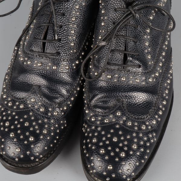 Närbild på nitar och mönstrat svart läder på brogues