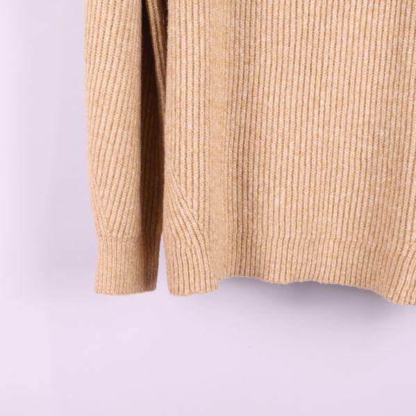 Närbild på ärmslut och nederkant stickad tröja