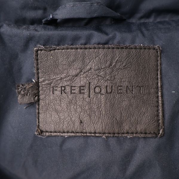 Närbild på FREQUENT logotyp i jackans krage