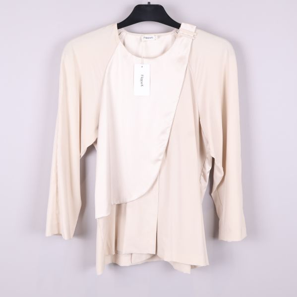 Framsida av beige omlottblus på galge mot vit bakgrund