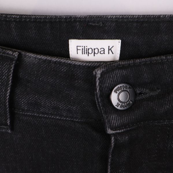 Närbild på Filippa K-logga och jeansknapp framtill