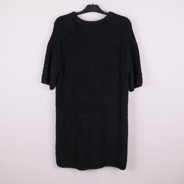 Svart stickad tröja fotad bakifrån på galge