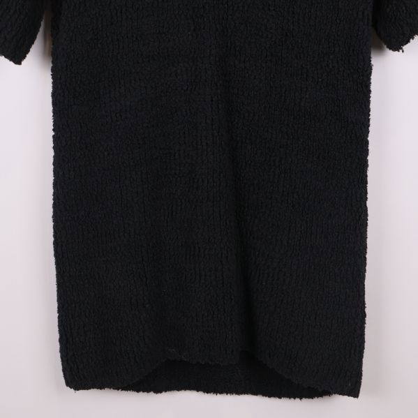 Närbild på nederkant av svart stickad tröja