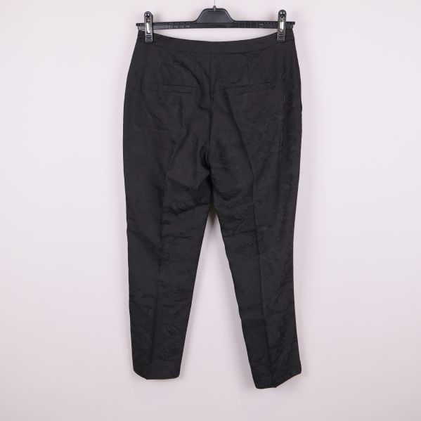 Svarta mönstrade byxor bakifrån på galge mot ljus bakgrund