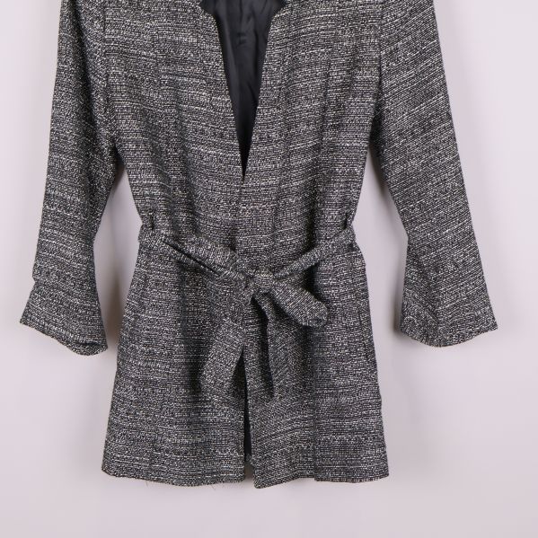 Närbild på nederdelen av svartvit kavaj med knytskärp