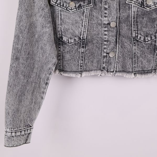 Närbild på ärm och rå nederkant av jeansjacka