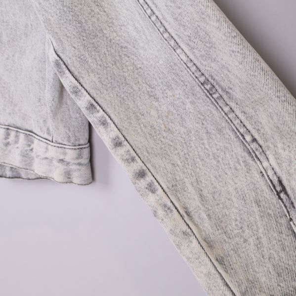 Detalj av vänster ärm med liten fläck på ljus jeansjacka