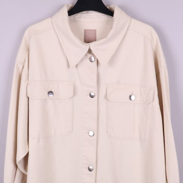 Närbild på övre delen och fickor av beige overshirt