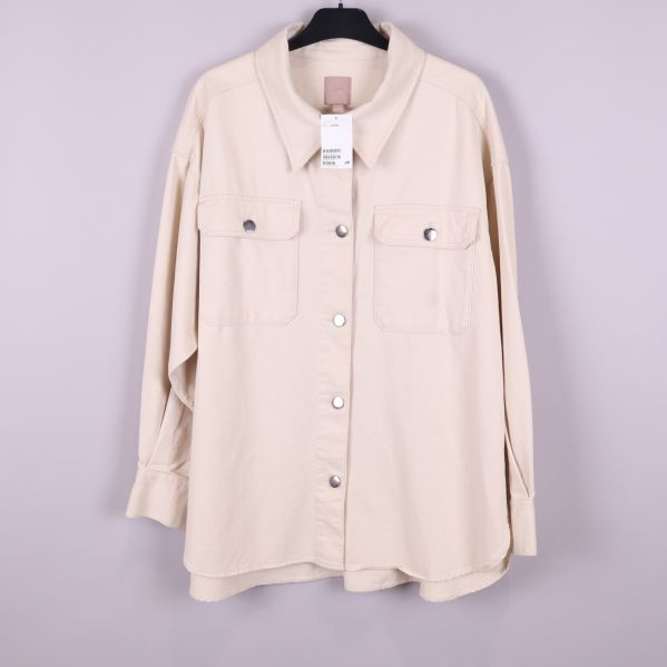 Framsidan av beige overshirt på galge med fickor
