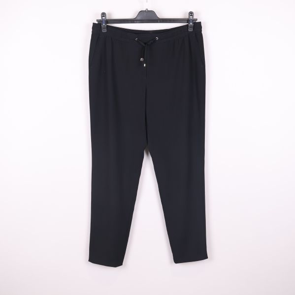 Svarta byxor hängande mot ljus bakgrund, hel framsida