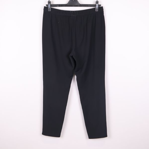 Svarta byxor hängande mot ljus bakgrund, hel baksida