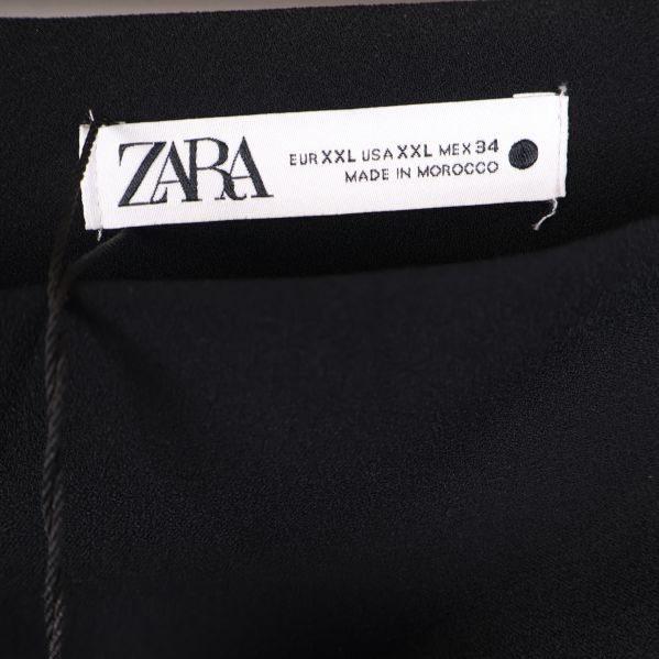 Närbild på Zara-logga i svart text på vit etikett
