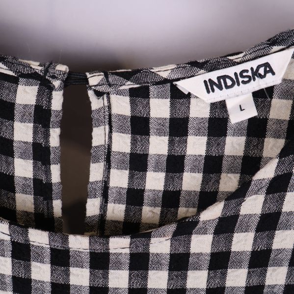 Närbild på Indiska-märkeslapp i halsen och rutmönster