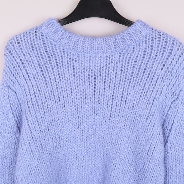 Närbild på hals och axlar på ljusblå stickad tröja