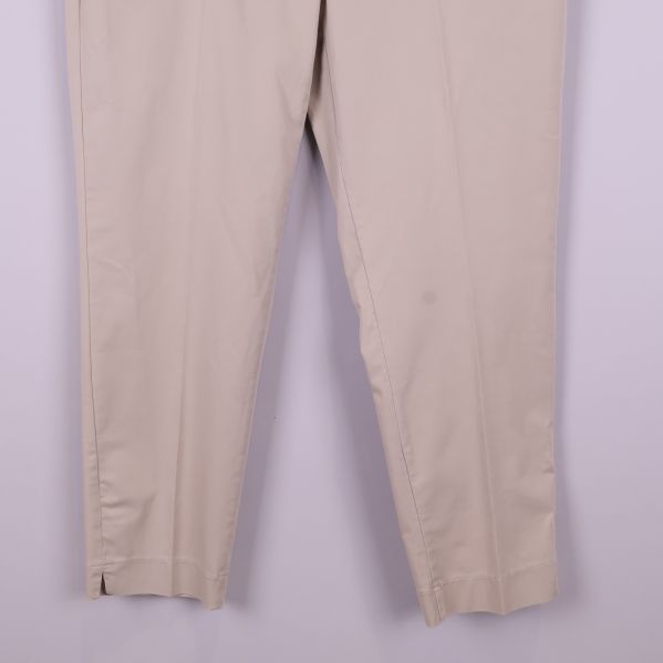 Närbild på nedre delen av benen på beiga byxor