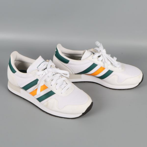 Sneakers från sidan som visar sidoränder i grönt och orange