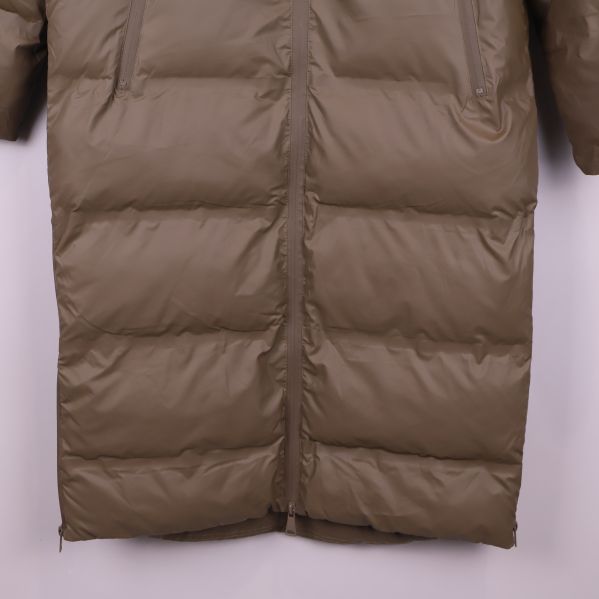Närbild på nederkanten av beige pufferjacka