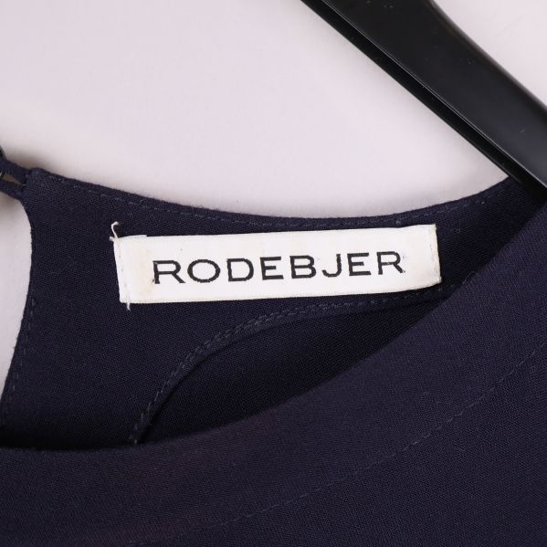 Närbild på etikett med Rodebjer logotyp i halsen