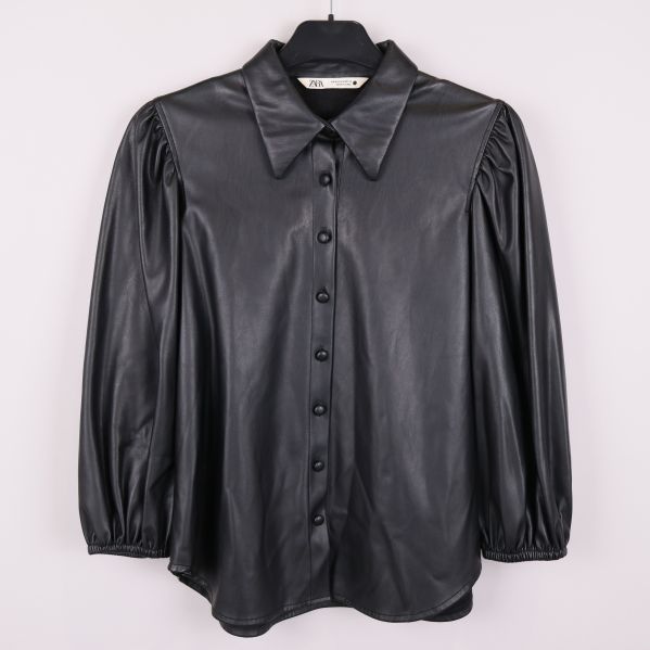 Svart konstläderblus med puffärmar sedd framifrån