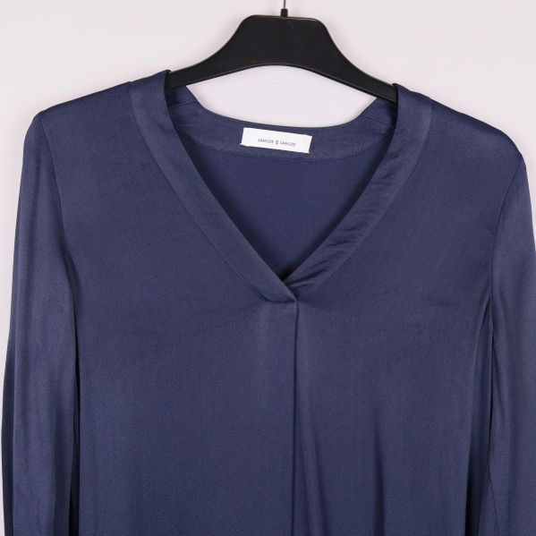 Närbild på v-ringning och axelparti av blå klänning