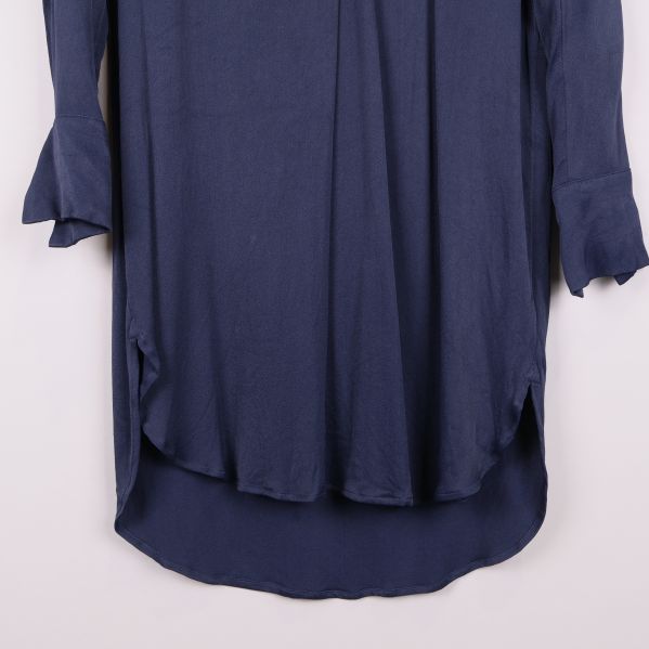 Nederkant och ärmslut på blå klänning i närbild