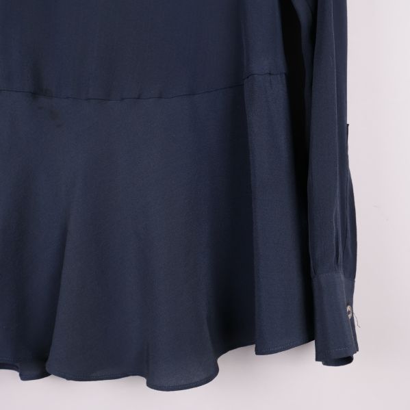 Närbild på blusens nederkant och ärmslut med knapp