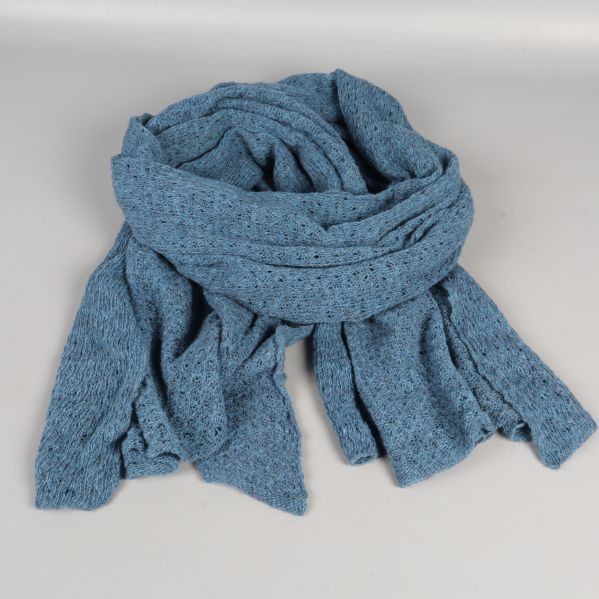 Blå stickad halsduk hoprullad på ett bord