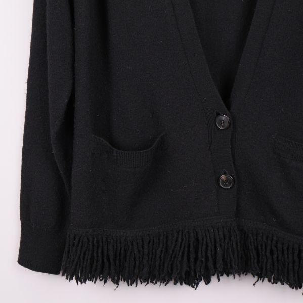 Närbild på fransar och fickor på koftan