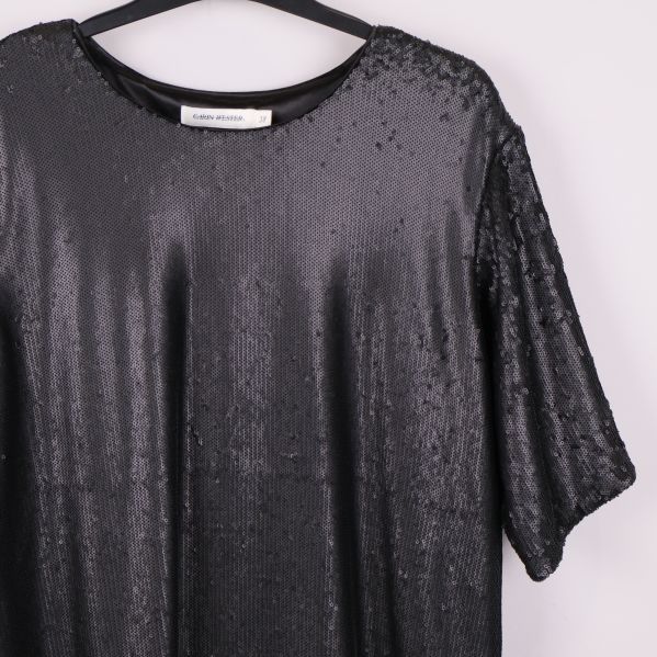 Detaljbild på framstycke med täta svarta paljetter