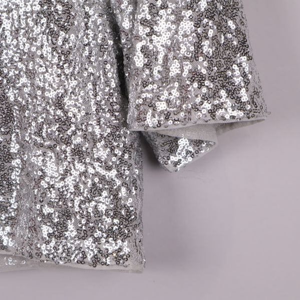 Närbild på paljetter och ärmslut av toppen