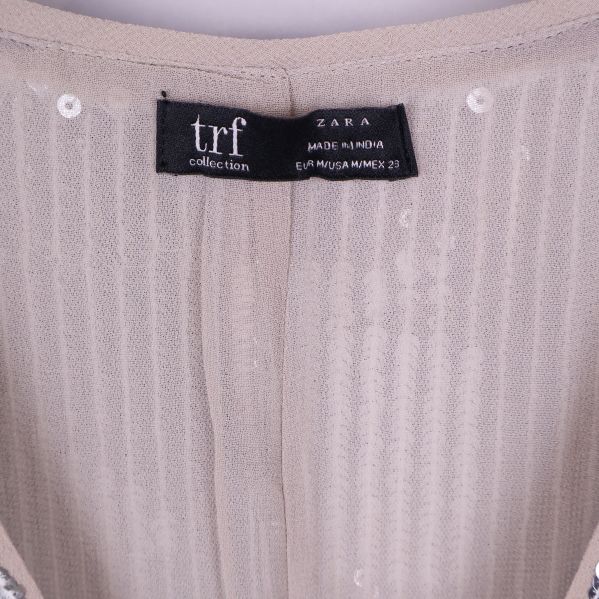 Närbild på svart etikett trf Zara i nacken på paljett tunika