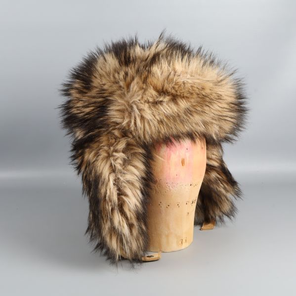 Fuskpälsmössa på trähuvud fotograferad från snett framifrån