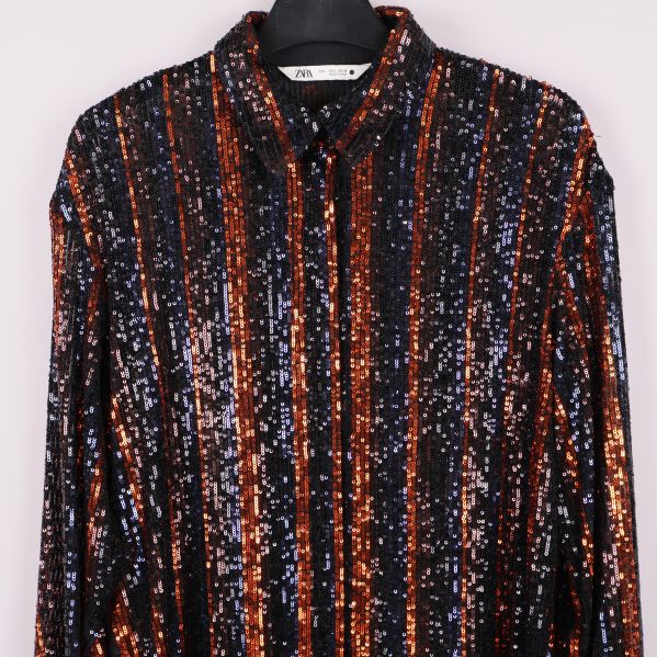 Närbild på skjortans överdel och krage med paljetter