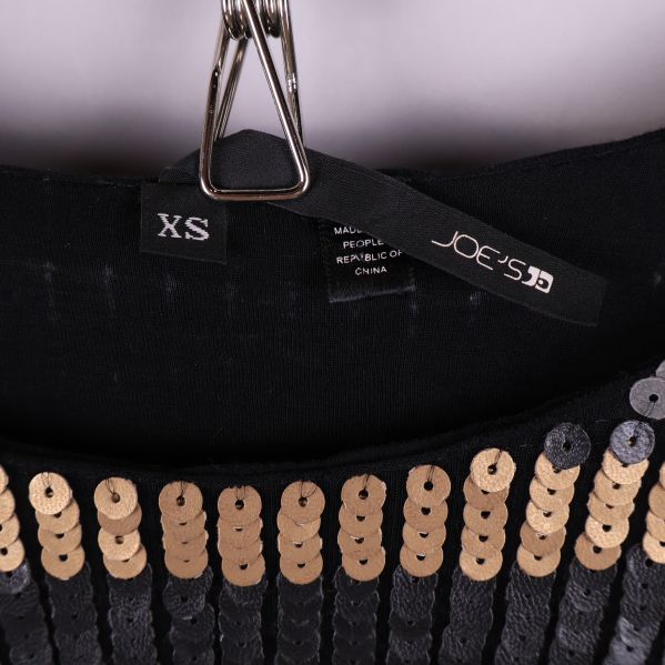 Storleks- och märkesetikett samt halsringning på paljettopp