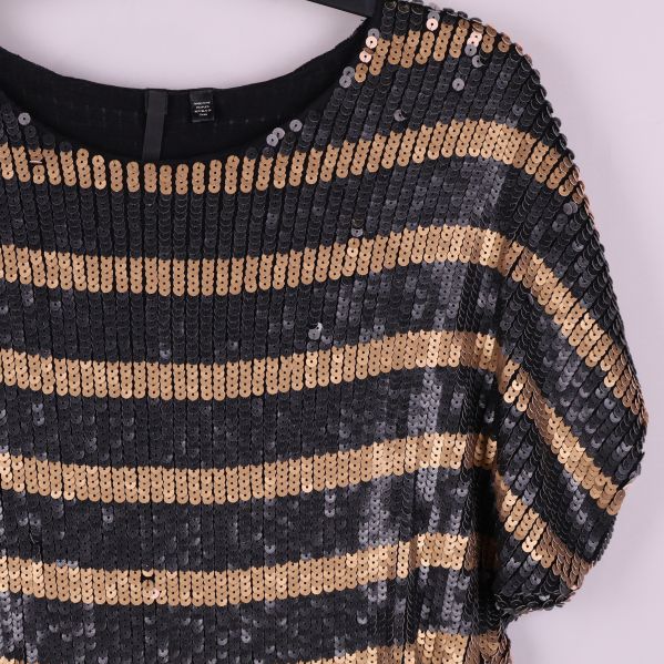 Närbild på axel och paljettränder samt struktur på toppen