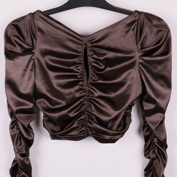 Närbild på draperad framsida av brun glansig topp