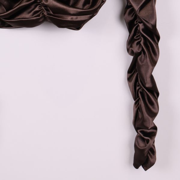 Närbild på rynkad lång ärm av brun topp