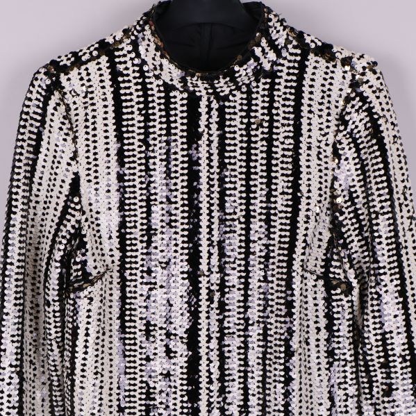 Närbild av hög krage och paljettmönster på blus