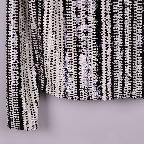 Närbild av ärmslut och paljettmönster på blus