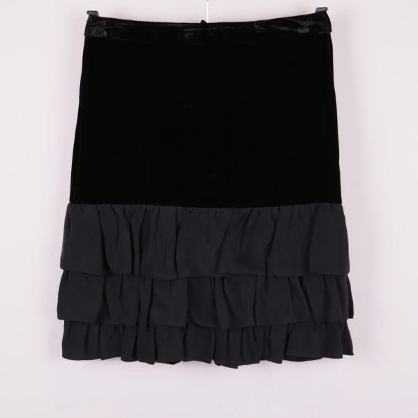 Kort svart kjol med sammetsliv och volanger framtill