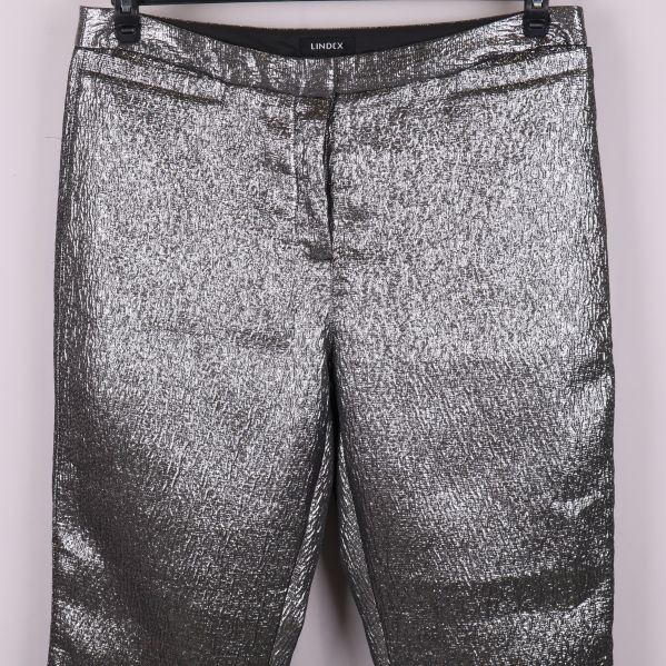 Midjedetalj och blixtlås på silverfärgade byxor