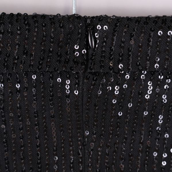 Närbild på dragkedja bak på svart paljettopp